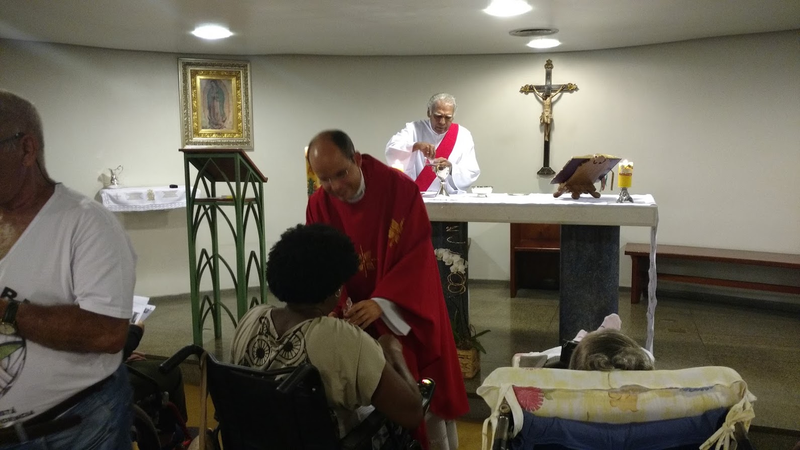 Padre Reynaldo recebe as ofertas das mãos de Maria Helena, membro da FCD. 