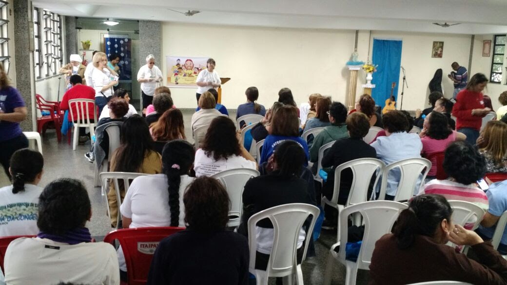 Membros da Catequese Especial (Fátima e Rosali). Igreja de São Lourenço. Salão paroquial. Cerca de 50 pessoas sentadas ouvindo a palestra. 