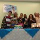 Grupo de surdos em volta da mesa com um bolo com o desenho de Nossa Senhora de Fátima. todos cantam os parabéns em LIBRAS.