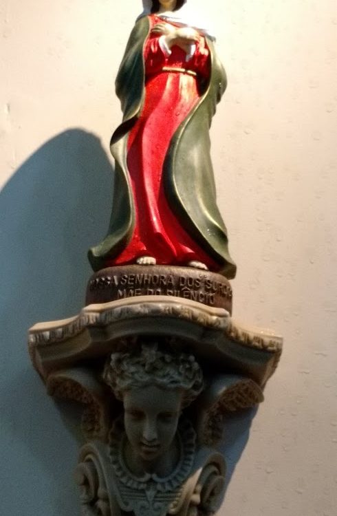 Imagem de Nossa Senhora dos Surdos, Mãe do Silêncio no altar lateral da Basílica do Imaculado Coração de Maria no Méier. Ela tem o tamanho de 30 cm, vestido de cor vermelha e manto verde. Tem as mãos cruzadas no peito, tem um olhar terno e sereno.